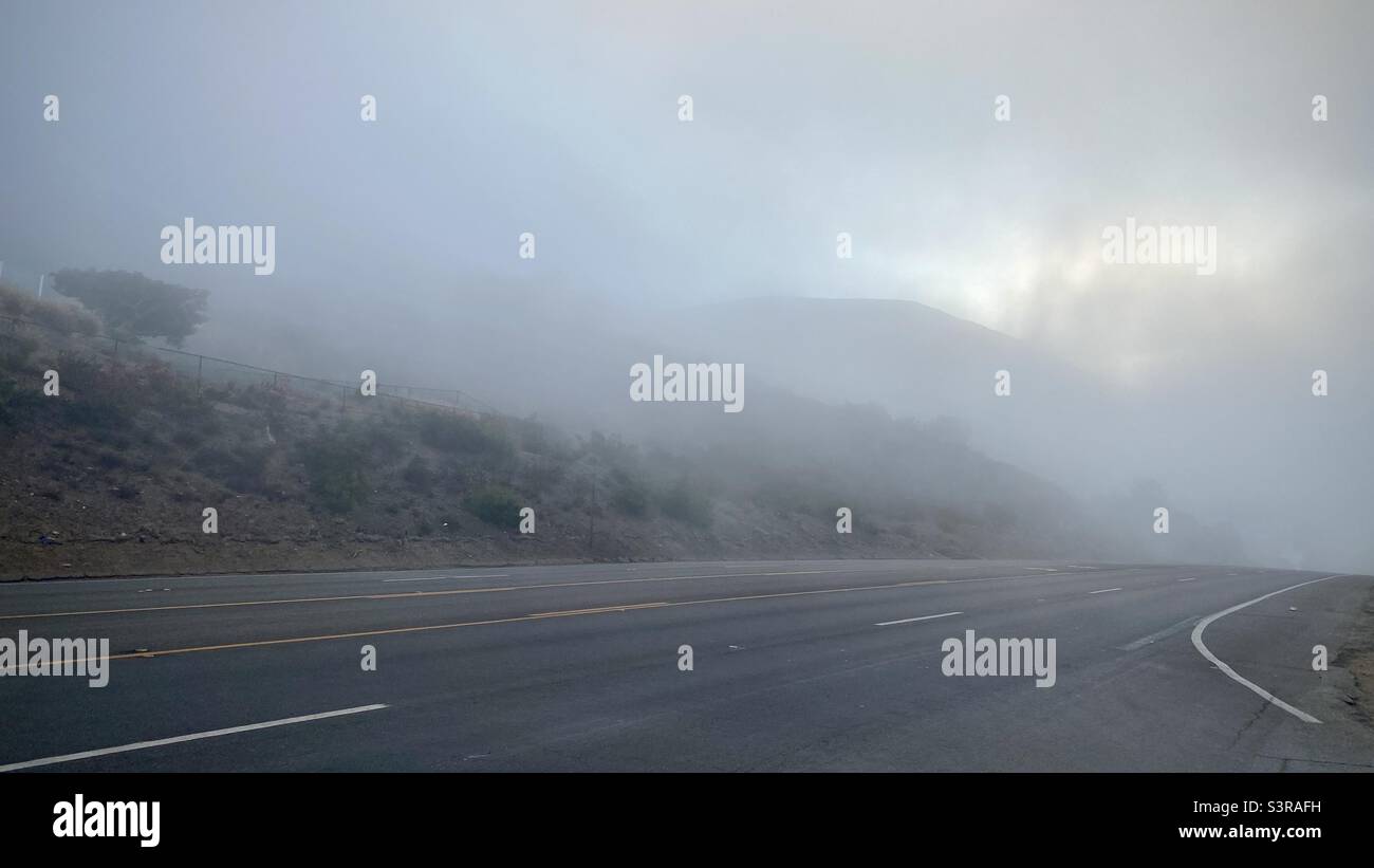 Pacific Coast Highway recedes into early morning fog near El Matador State Beach, Southern California Stock Photo