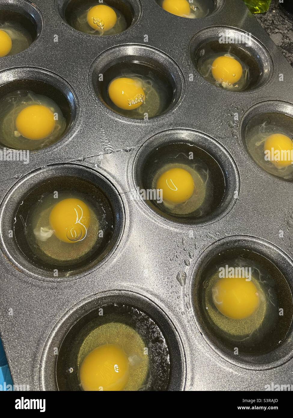 Eggs in muffin pan for poaching Stock Photo Alamy