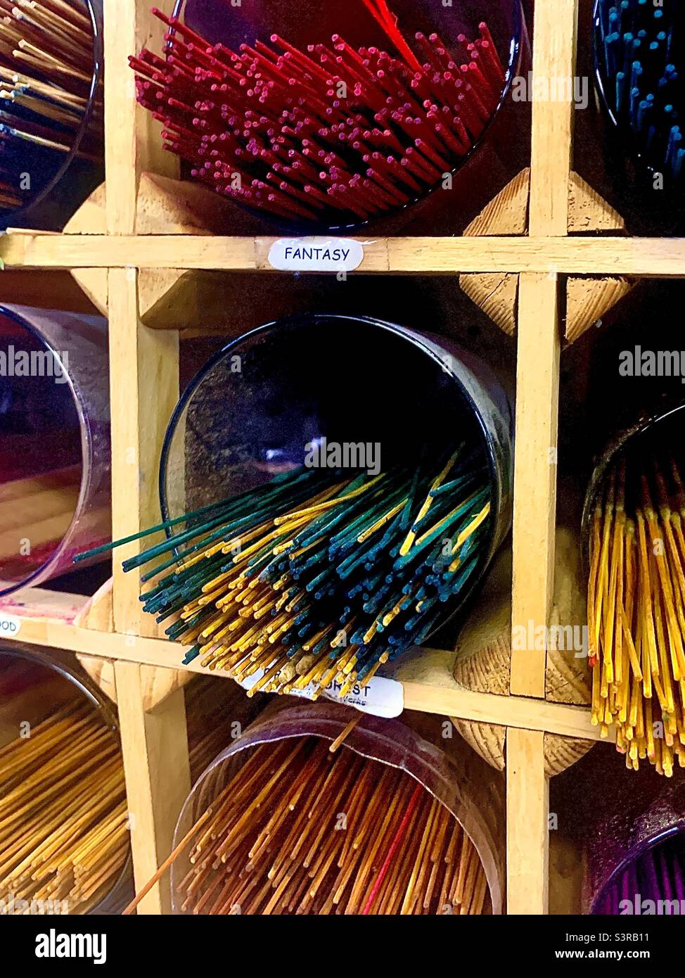 Grid of wooden shelving displays colorful variety of incense sticks