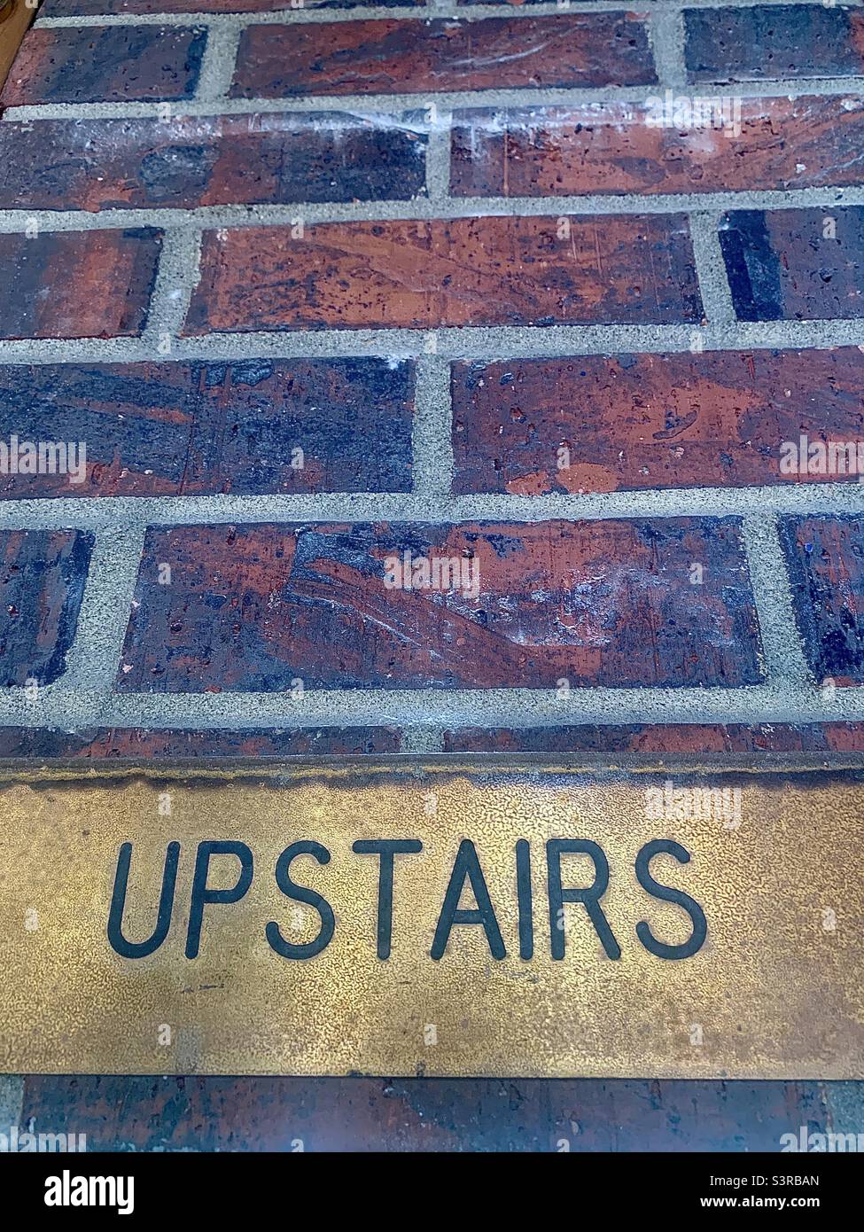 Gold Plaque with Black Letters, UPSTAIRS, and Brick Wall Woth Negative Space - Smartphone Captured Stock Image