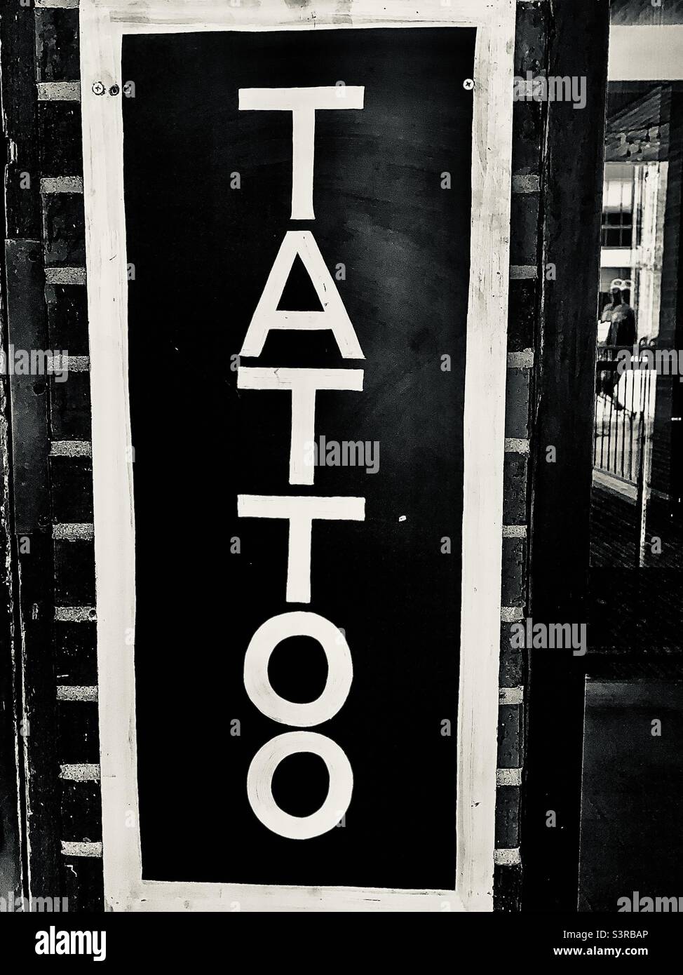 Black and White TATTOO Sign and Brick Wall with Negative Space - Smartphone Captured Stock Image