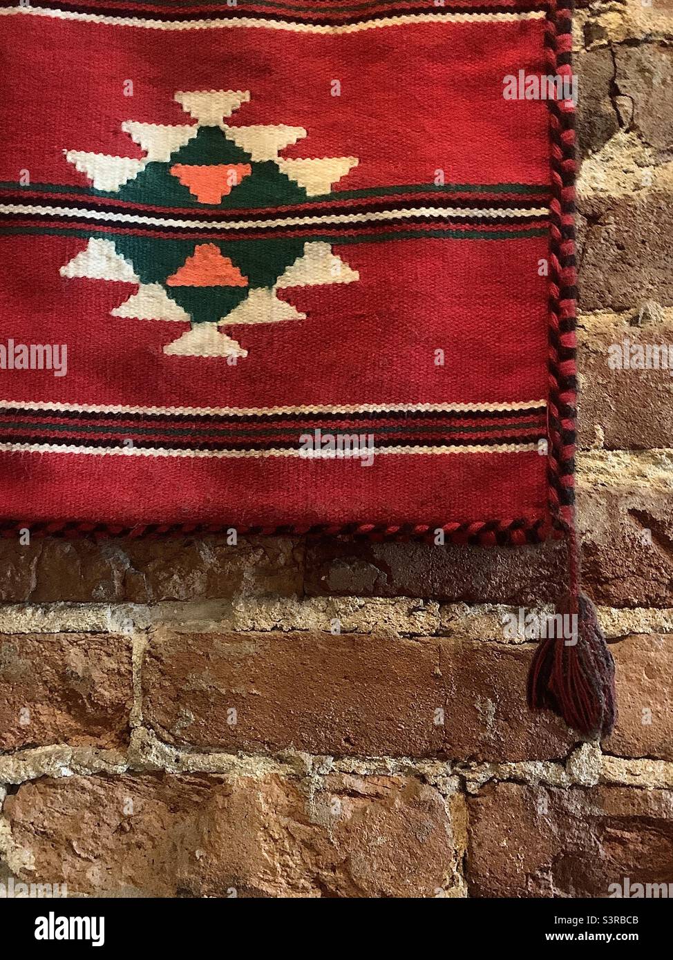 Red Ethnic Textile Against Brick Wall - Smartphone Captured Stock Image