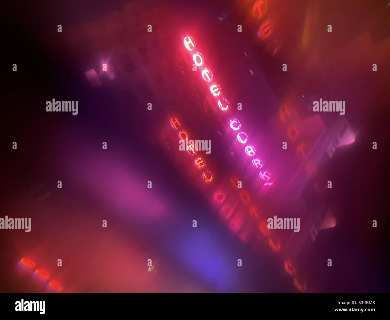 LOS ANGELES, CA, AUG 2021: abstract pattern in shades of pink and red, created with prism viewing neon sign at the Hotel Clark in Downtown at night - Smartphone Captured Stock Image