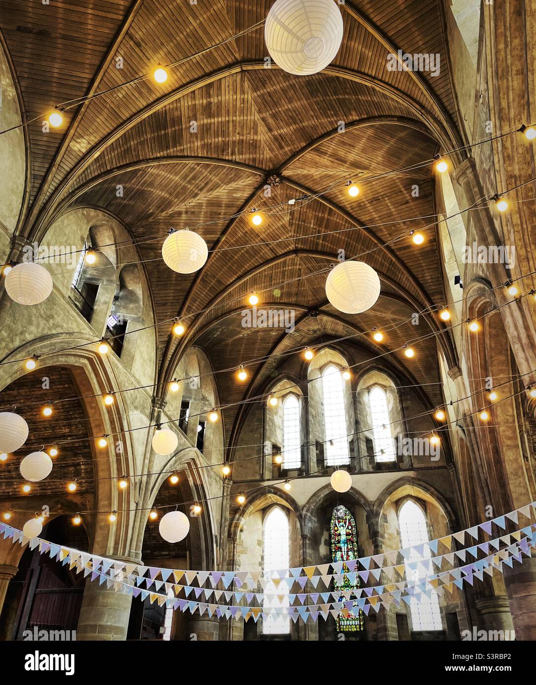 ‘Let there be light’ a church is beautifully decorated for a wedding with bunting, lanterns and lights Stock Photo