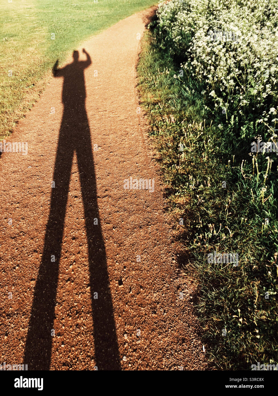 Long shadow of a man on a red soil path Stock Photo