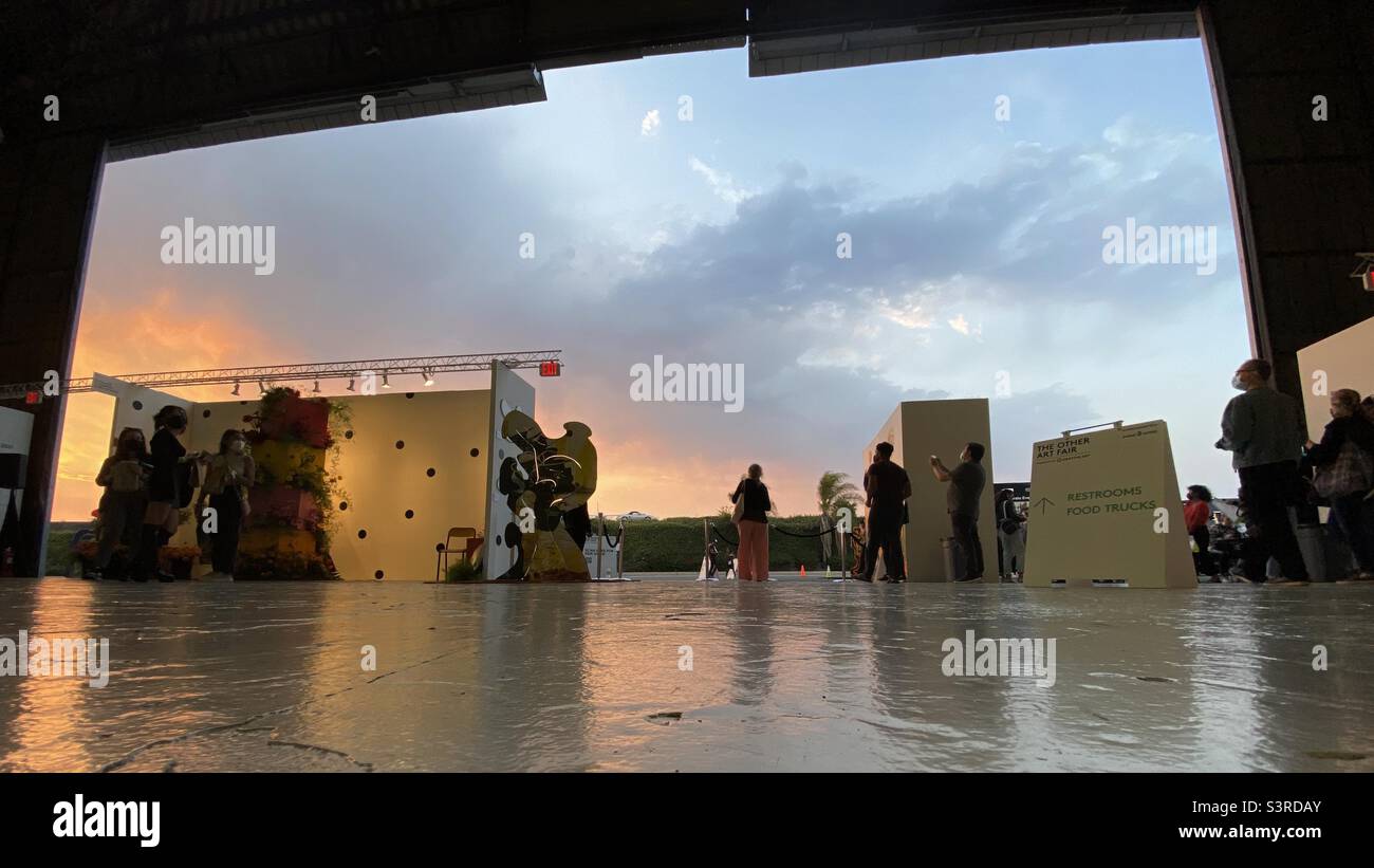 LOS ANGELES, CA, SEP 2021: silhouetted visitors to The Other Art Fair at Barker Hangar, Santa Monica Municipal Airport, with sunset sky visible through hangar doors Stock Photo