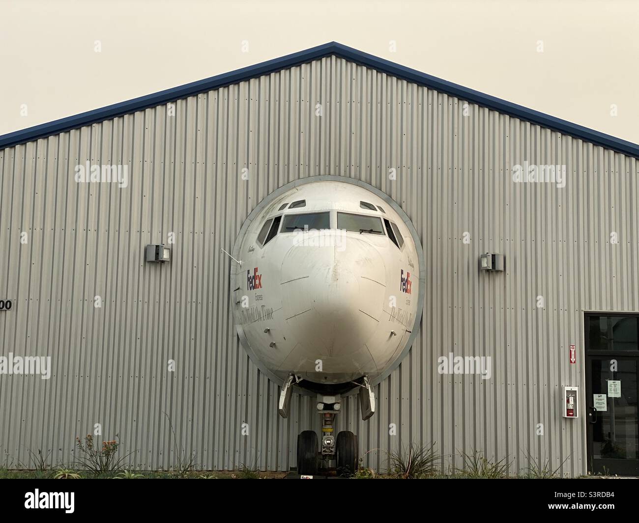 LOS ANGELES, CA, SEP 2021: front view, cockpit of jet aircraft used by FedEx appears to come through hangar wall to street at Museum of Flying, Santa Monica Municipal Airport - Smartphone Captured Stock Image
