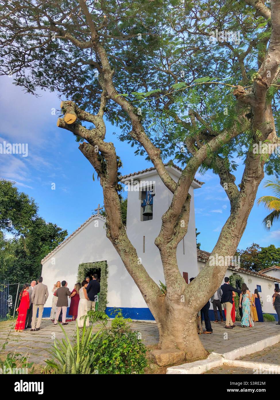 Wedding guests standing outside a small church in Buzios, Brazil. - Smartphone Captured Stock Image