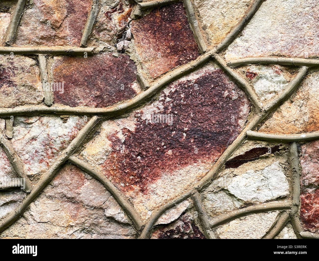 Uneven textured stone wall of a house built in 1935 with grapevine