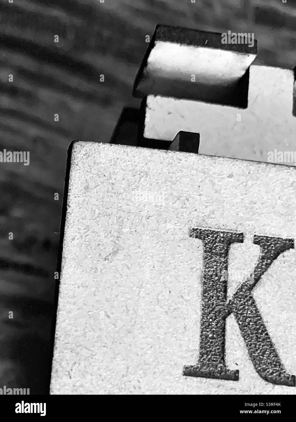 Black and white Wooden puzzle box with letter K and negative space - Smartphone Captured Stock Image