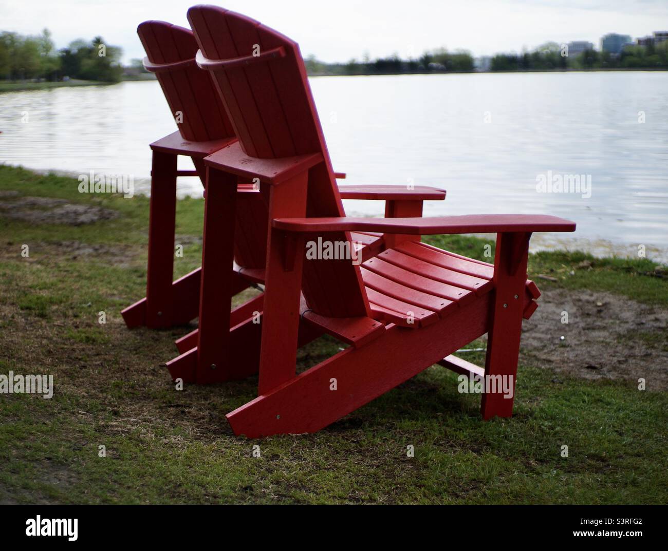 Two red Muskoka Chairs awaiting their next guest by Dow’s Lake. - Smartphone Captured Stock Image