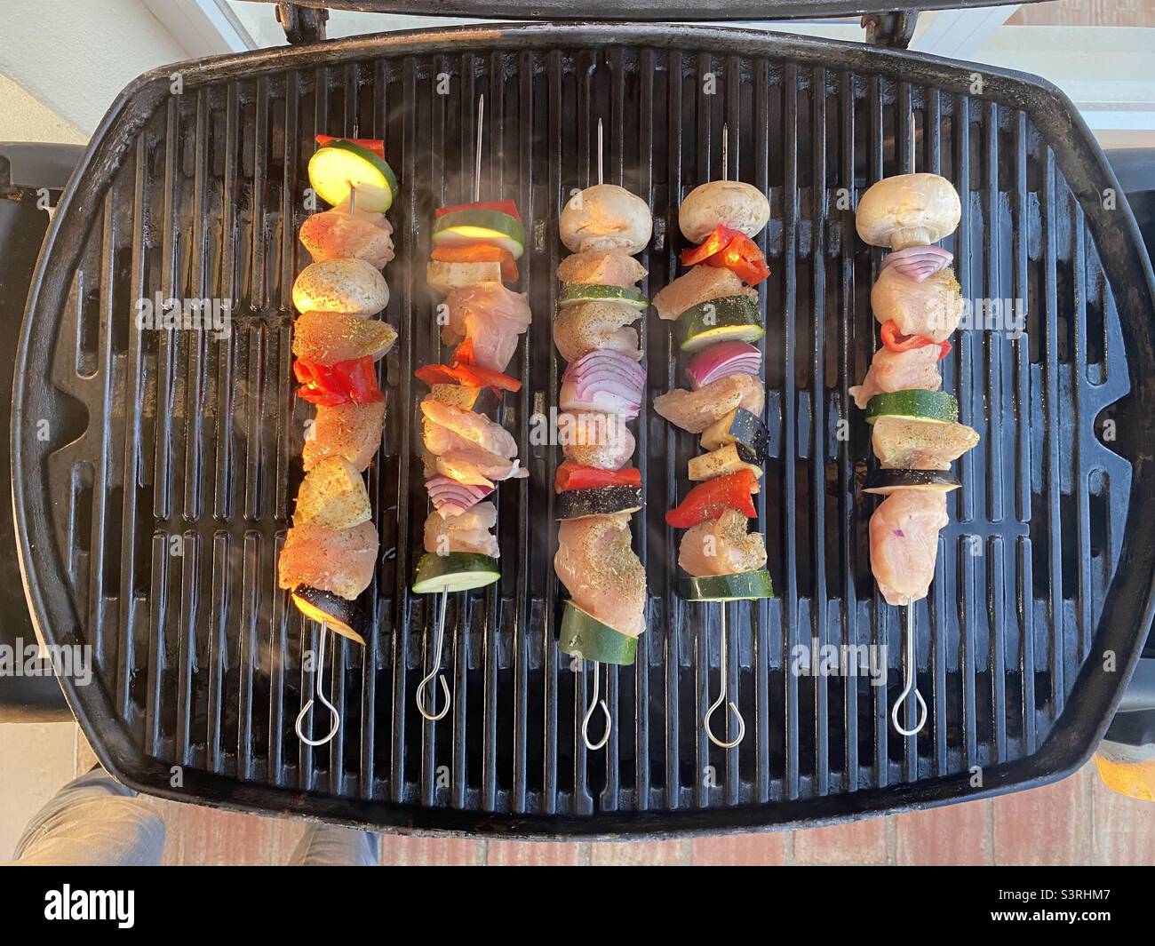 Chicken and vegetable kebabs cooking on a gas BBQ Stock Photo