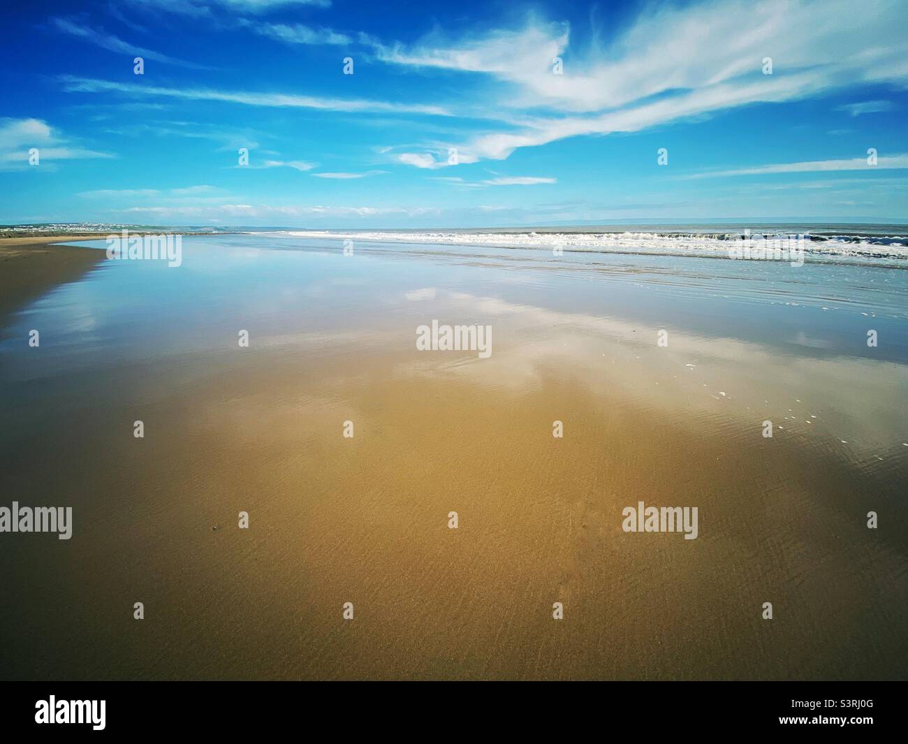 A landscape photograph of a sandy beach on a beautiful summer day with blue sky and clouds, with copy space. - Smartphone Captured Stock Image