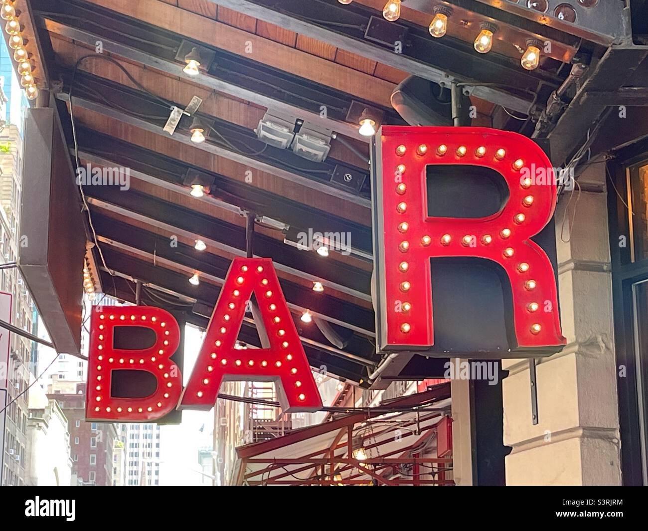 Oversized lighted letters spelling “BAR” at an outdoor dining area in Midtown Manhattan, New
