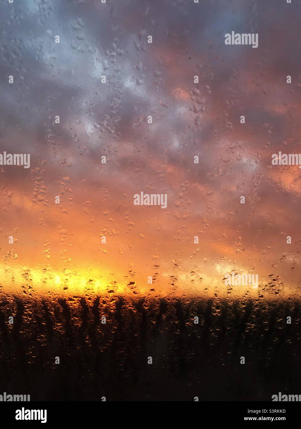 Sunrise looking through a window covered in condensation Stock Photo