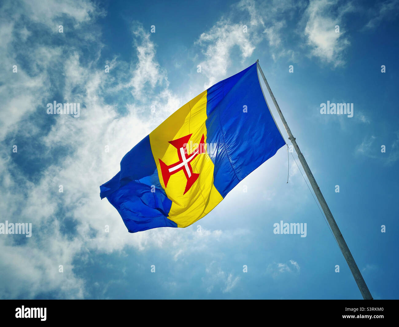 The flag of Madeira. Madeira is an island in the Atlantic Ocean and an Autonomous Region of Portugal. Blue=Environment. Yellow=Wealth & Climate. The Red Cross of Christ. Photo ©️ COLIN HOSKINS. Stock Photo