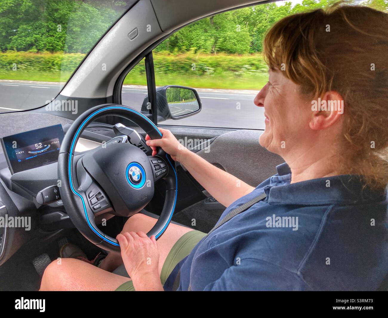 Middle aged woman driving a BMW i3 electric car Stock Photo