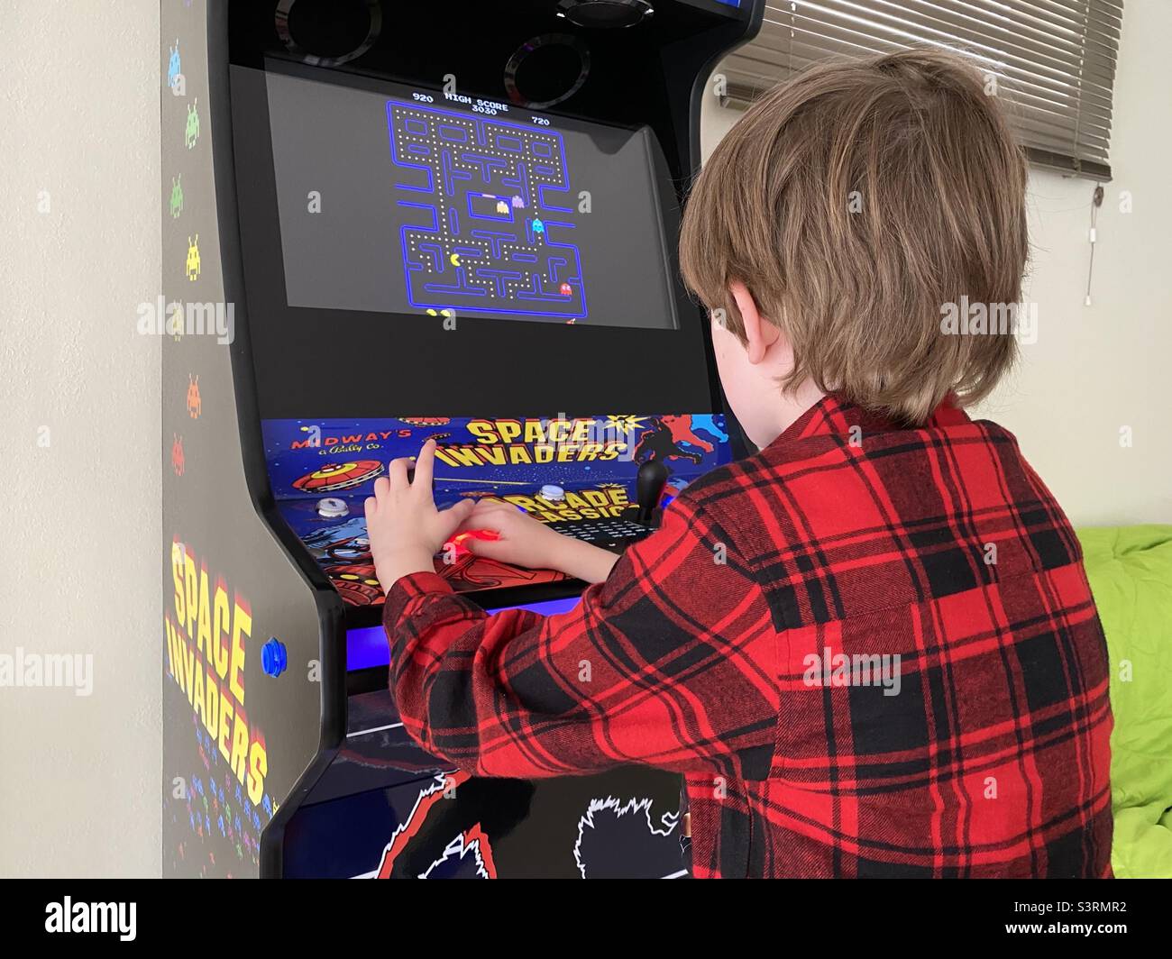 Young boy playing on a video arcade game Stock Photo