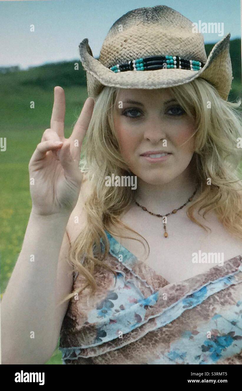 Girl with a straw hat, hi, hand signal, keeping fit, exercise, active, activity, action, 20’s, green field, woman, female, blonde, fun , pretty,pleasant , sunny day , hills, prairie, hat - Smartphone Captured Stock Image