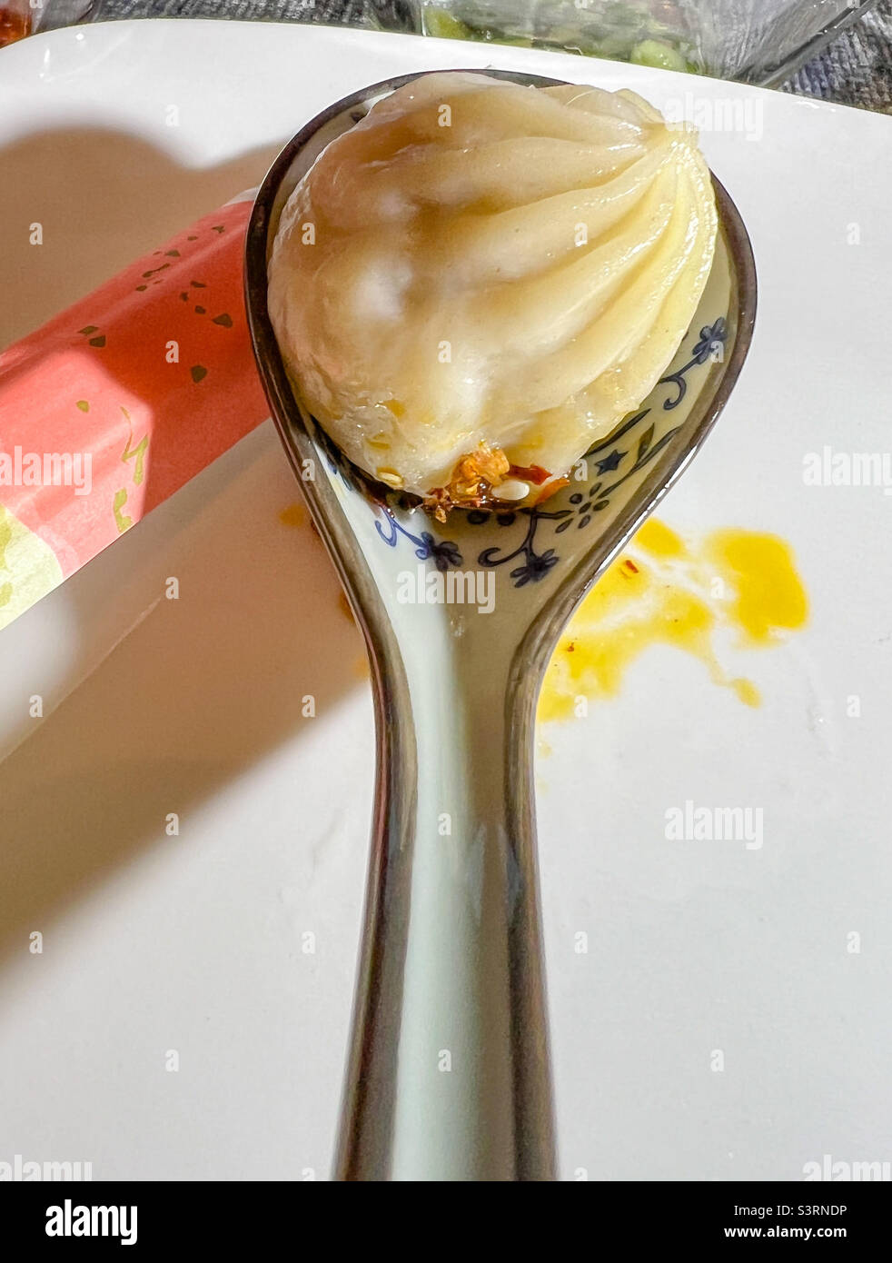 Steamed Chinese Soup Dumpling with ceramic soup spoon and chopsticks Stock Photo