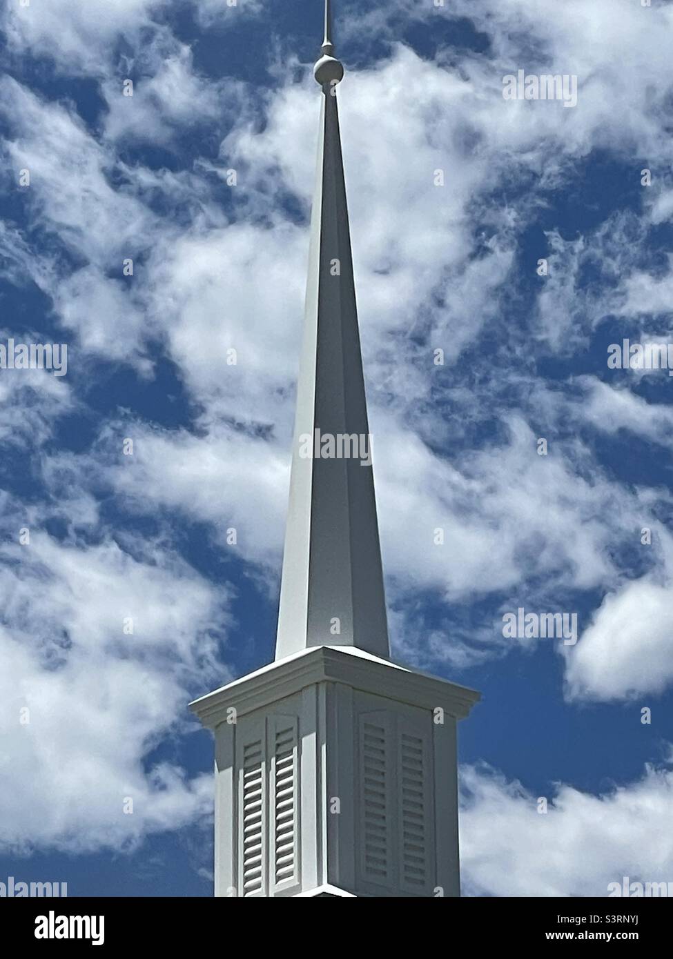 White church steeple beneath a sunny spring sky with lots of fluffy white clouds in Utah, USA. - Smartphone Captured Stock Image