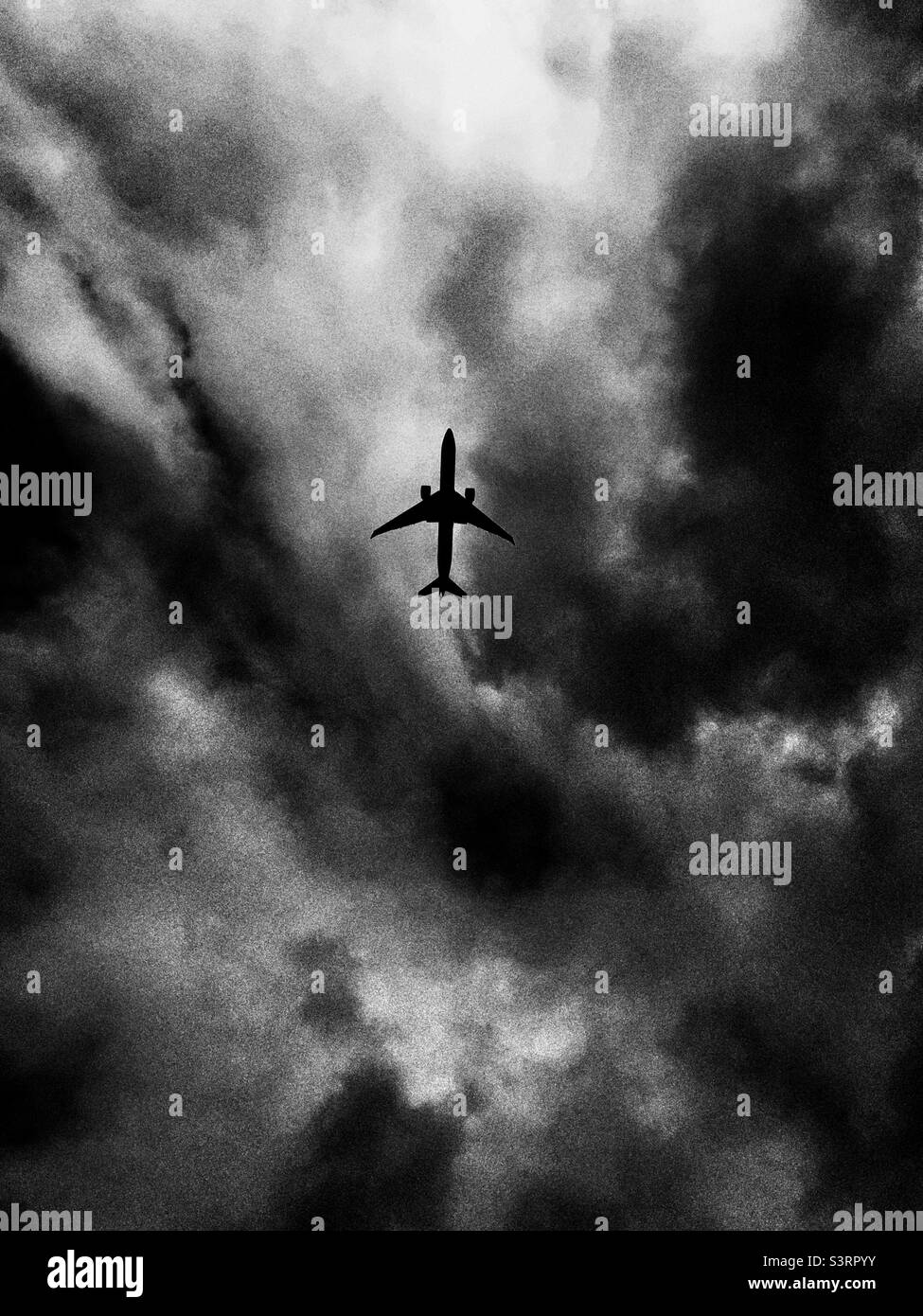 Airplane flying above against a dramatic cloudscape - Smartphone Captured Stock Image