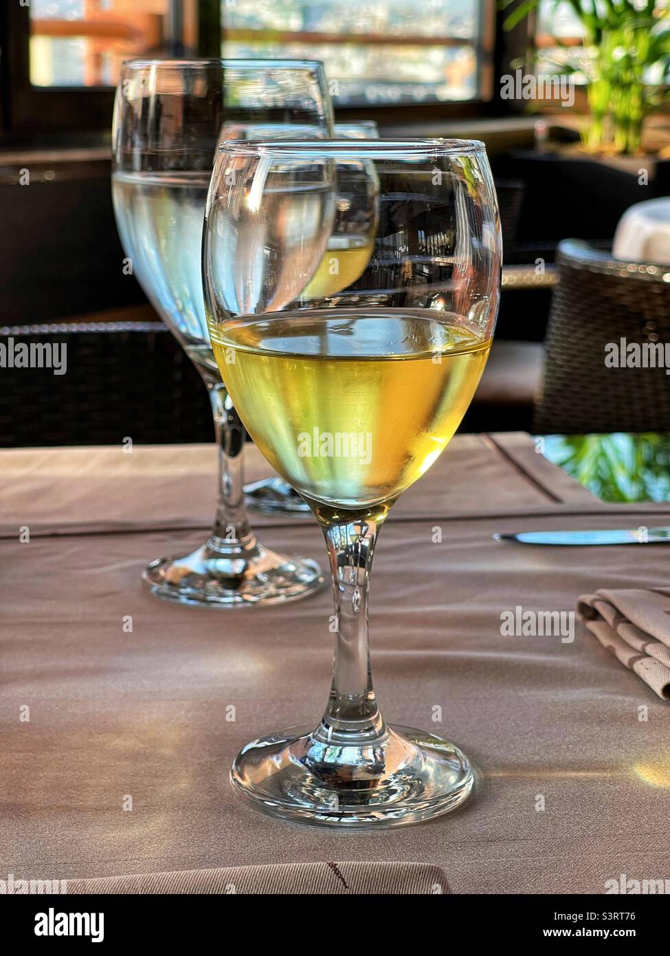 Glass of chilled white wine on a restaurant table at sunset - Smartphone Captured Stock Image