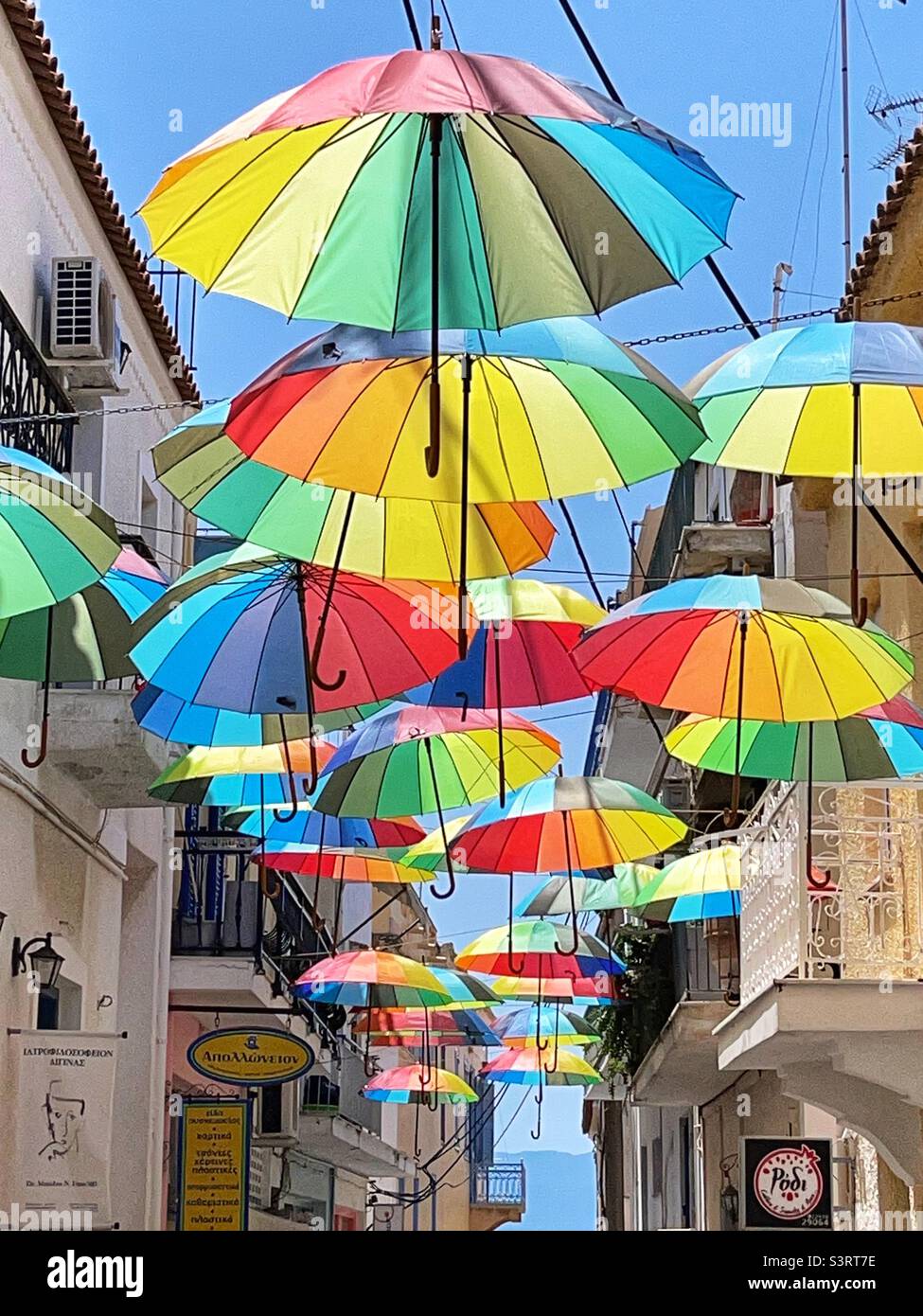 Coloured umbrellas suspended over a narrow street on the island of Aegina in Greece Stock Photo