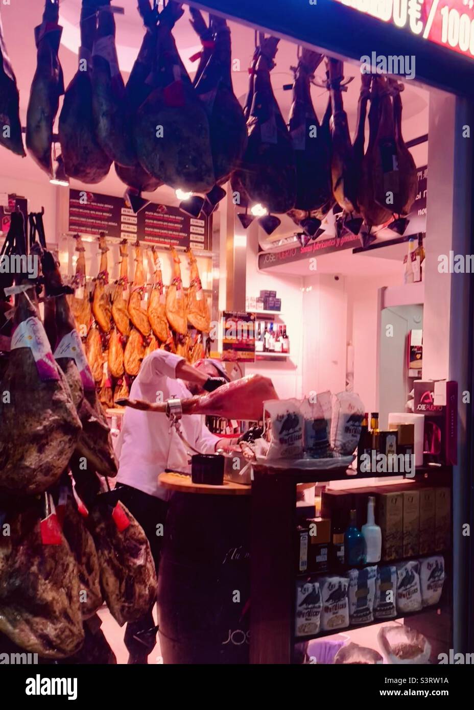 Spanish ham shop, Jamón de Bellota Ibérico, Malaga lit up at night Stock Photo