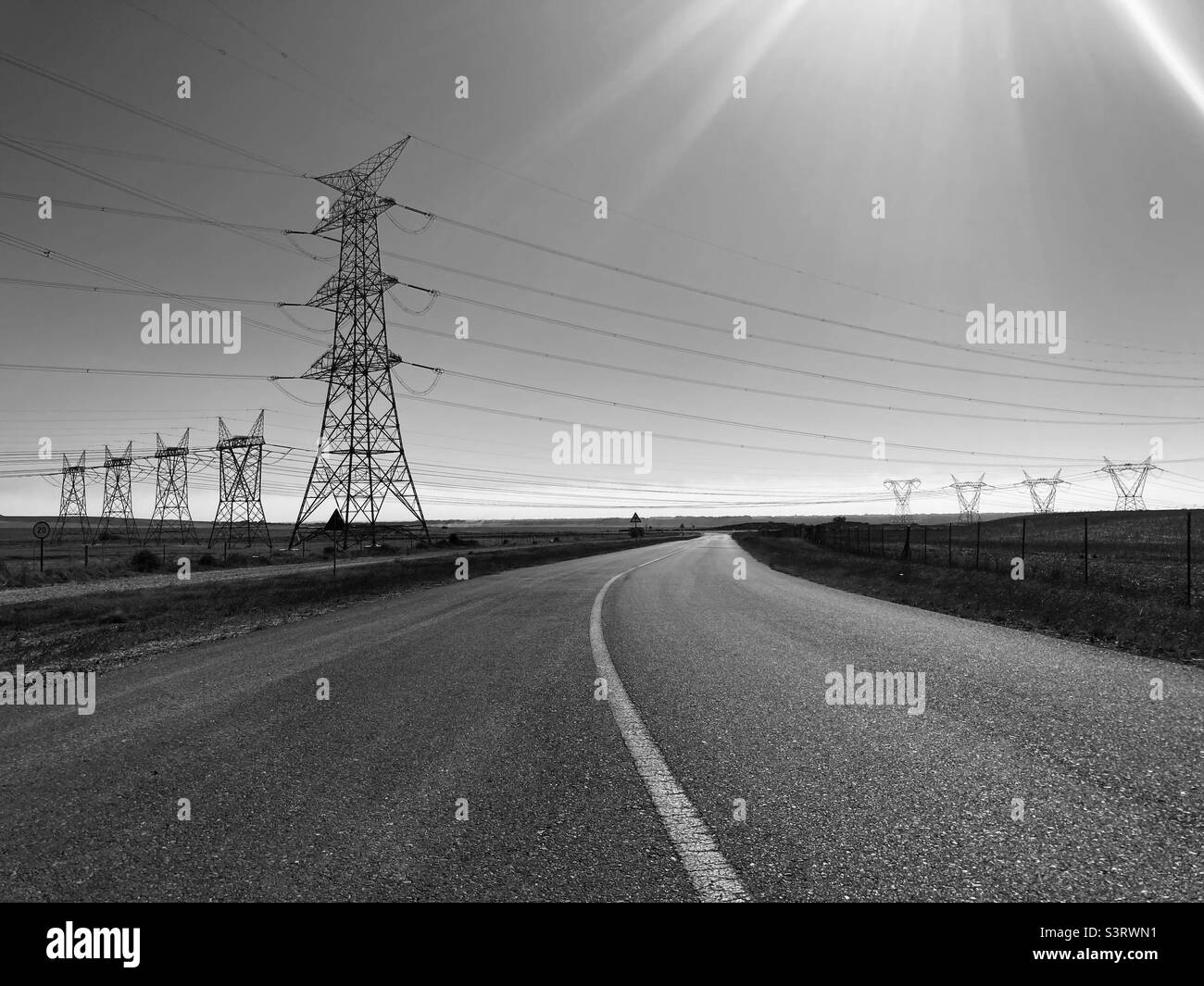 Electricity pylons high above the road Stock Photo