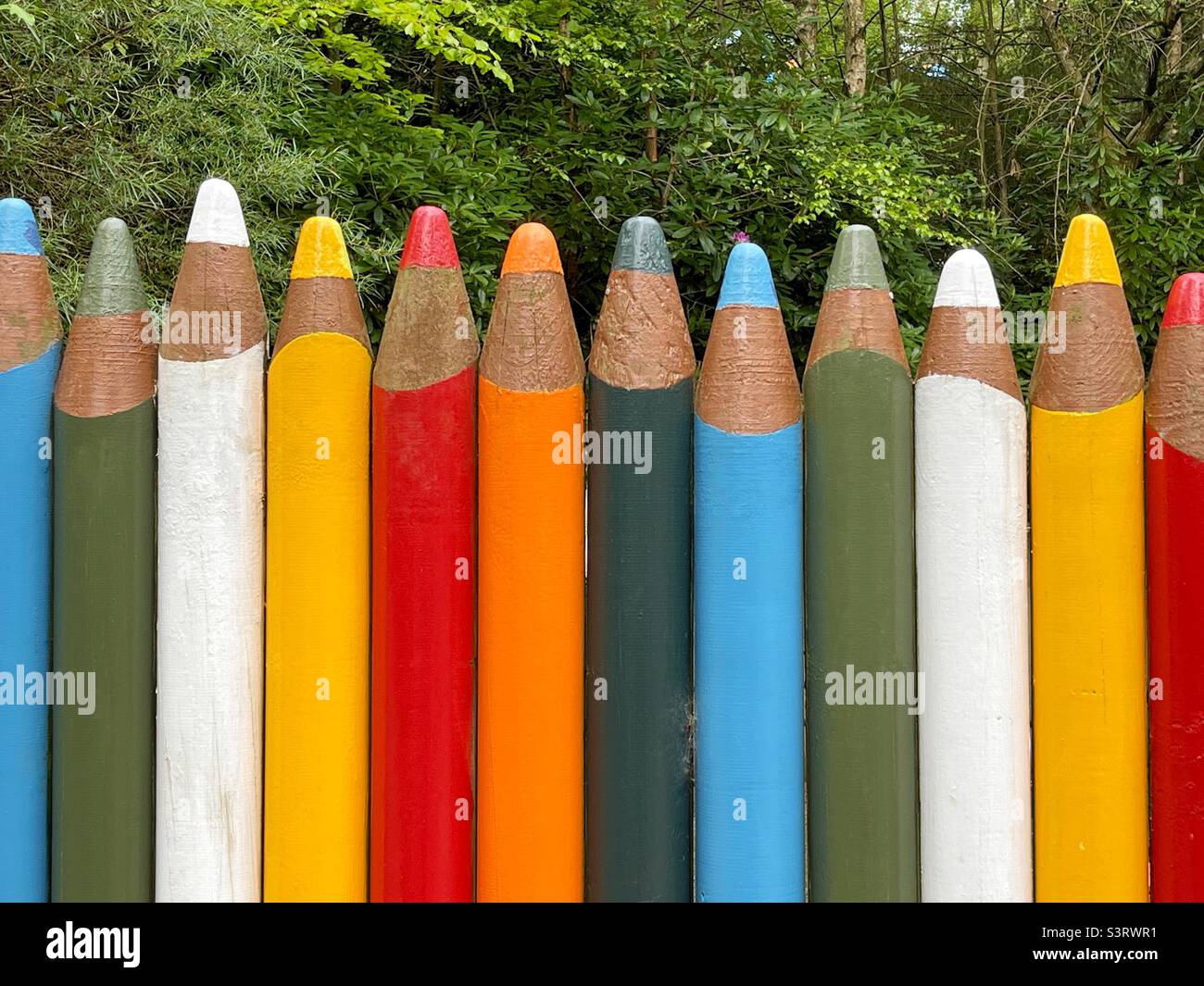 Wooden fence shaped and painted to resemble a row of coloured pencils Stock Photo