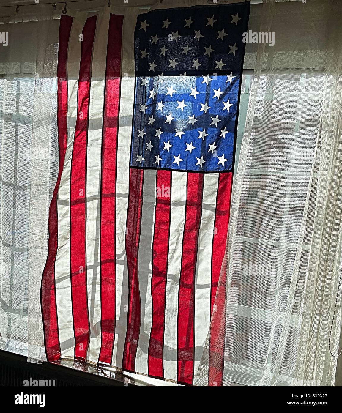 American flag on display in front of a casement window in a New York City apartment, 2022, USA - Smartphone Captured Stock Image