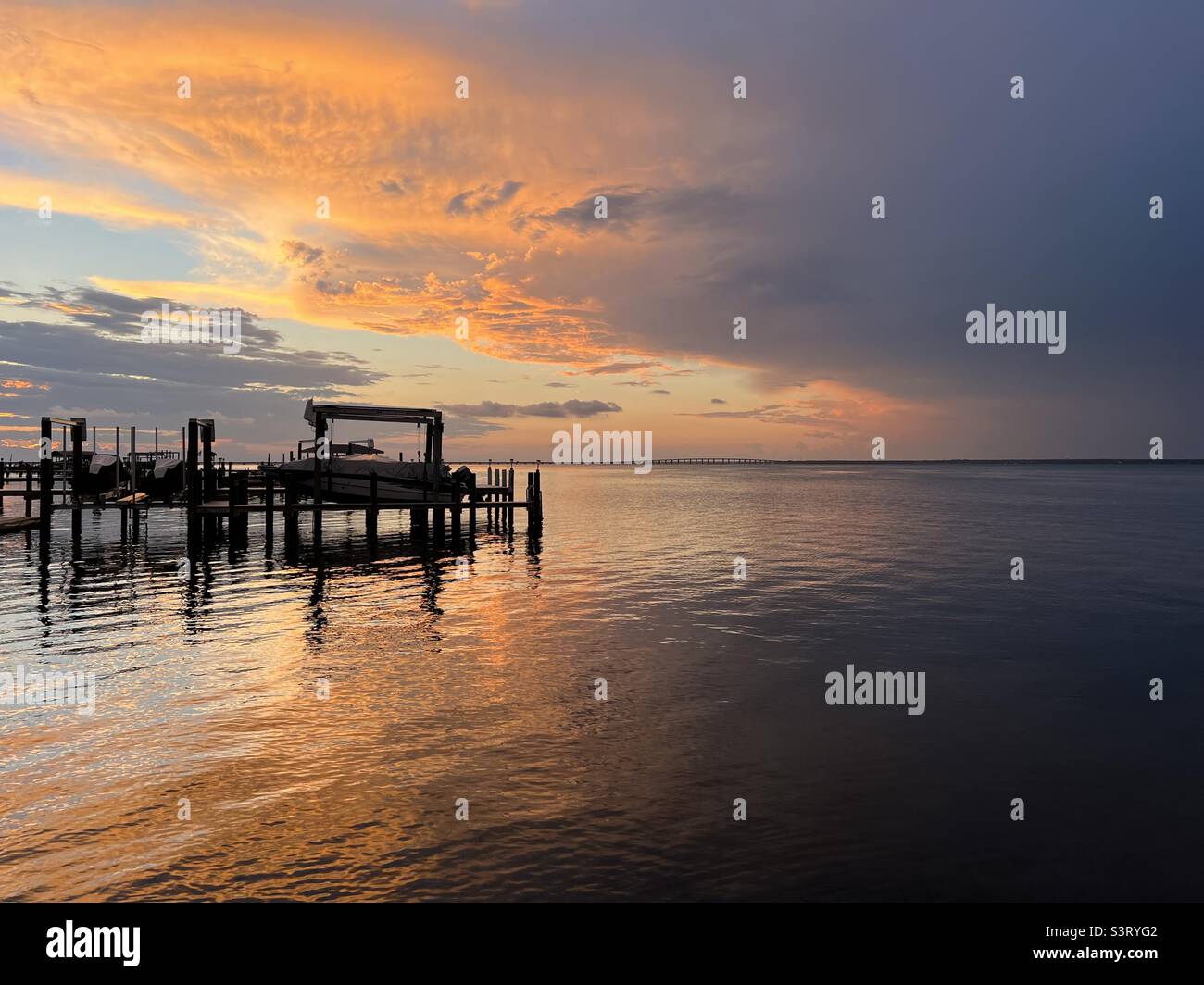 Dramatic sunset skies over boat dock on the water Stock Photo