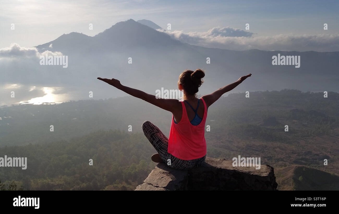 Young millennial girl meditates towards the rising sun in Bali, Indonesia Stock Photo