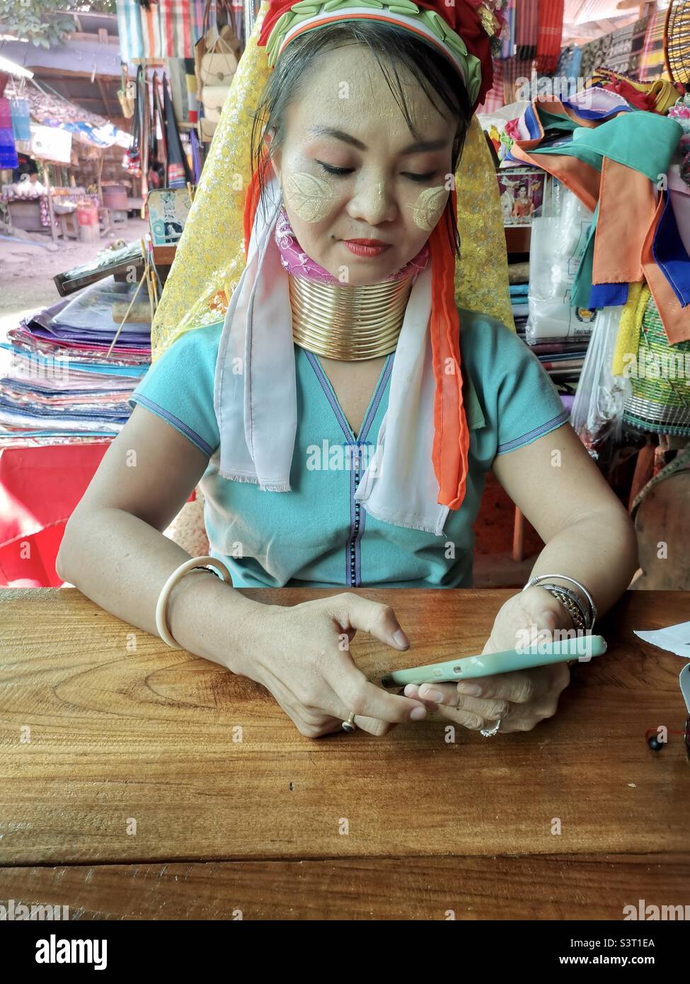 A Padaung / Red Karen long neck woman using her smartphone in Mae Hong Song province in Thailand. Stock Photo