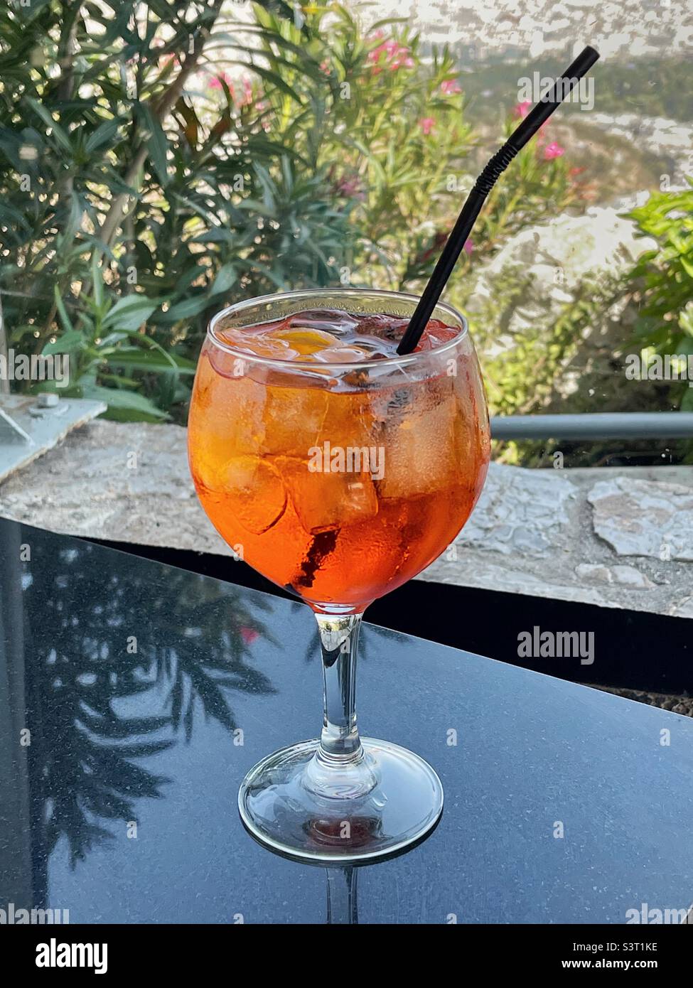 Aperol Spritz with ice and straw in a large glass in a mountain-top restaurant Stock Photo