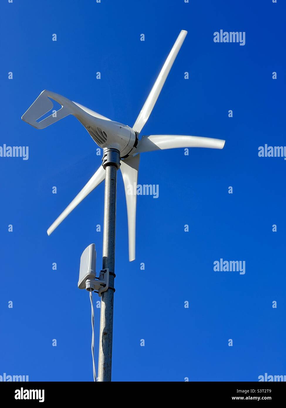 Small wind turbine against a clear, blue sky Stock Photo
