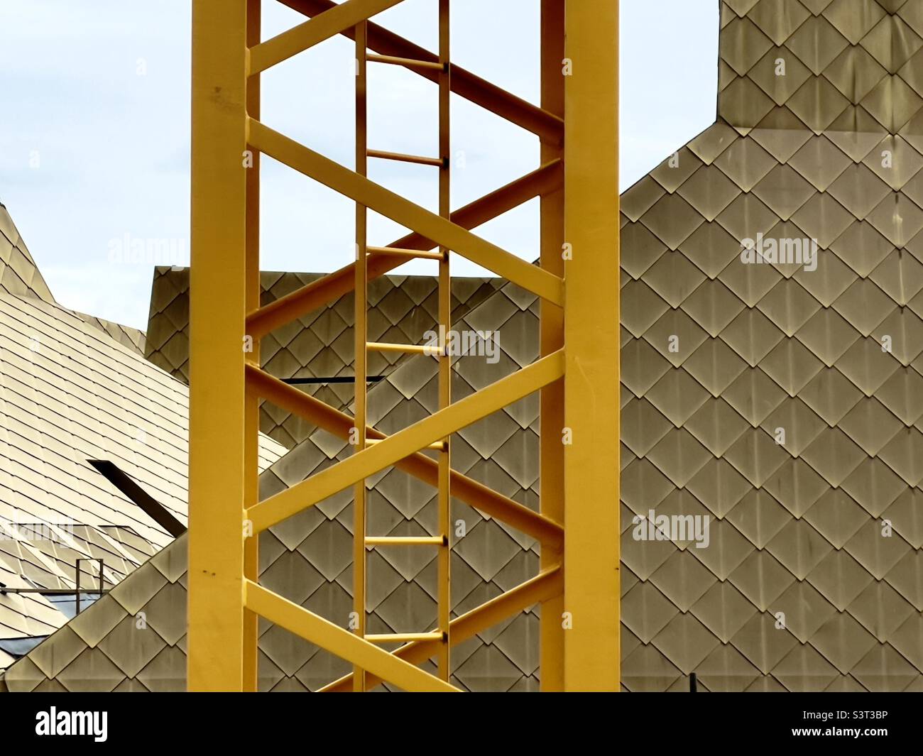 The lattice work of a yellow painted crane on a building site in Worcester UK with The Hive in the background. - Smartphone Captured Stock Image