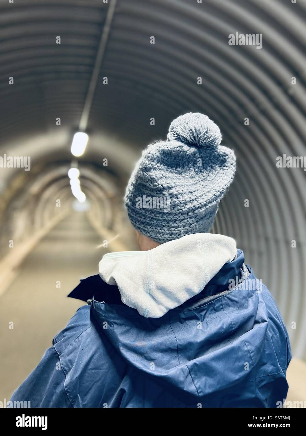 Rear view of woman wearing a knit hat walking in a tunnel Stock Photo