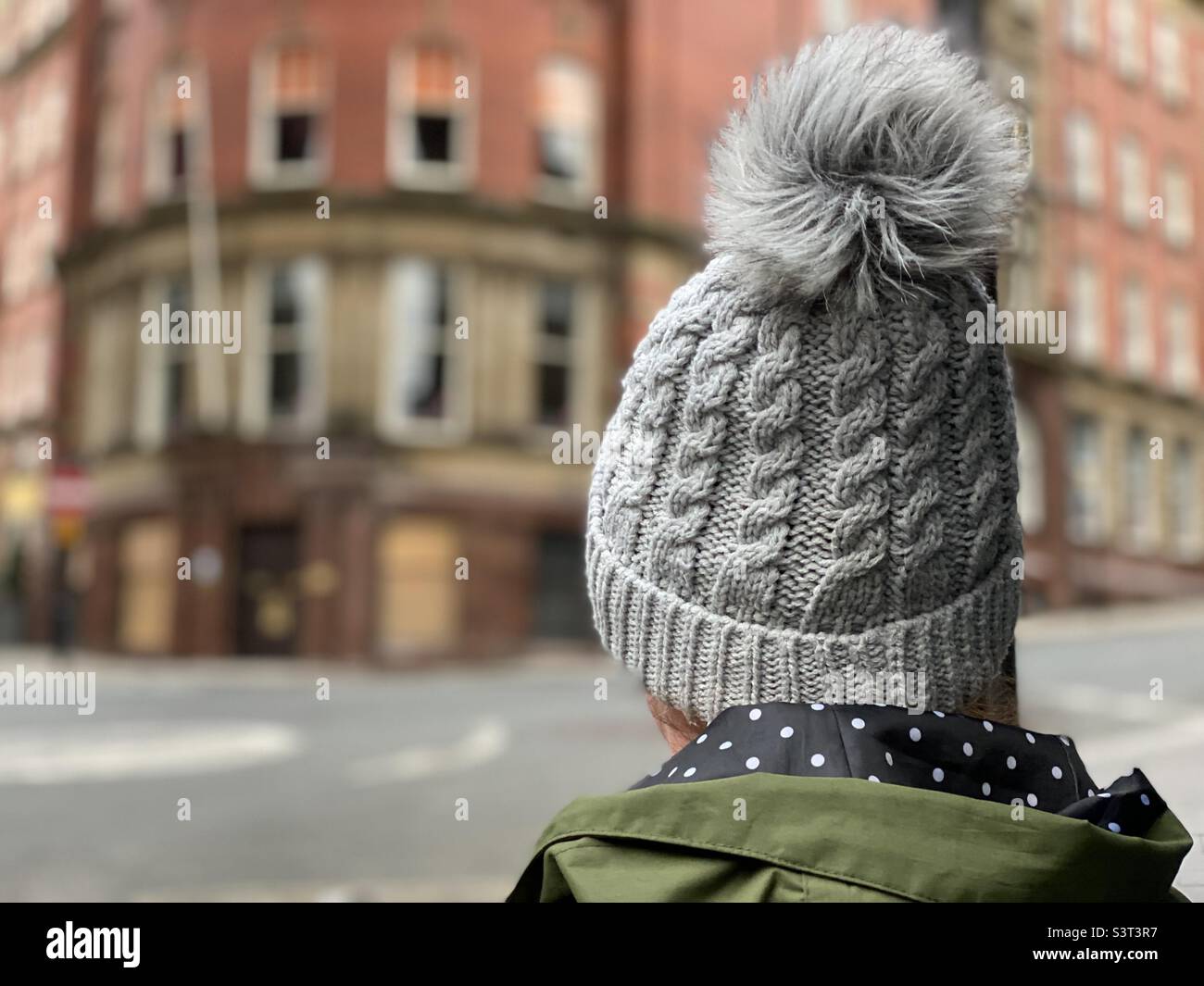 Rear view of woman wearing a knit hat amidst buildings Stock Photo