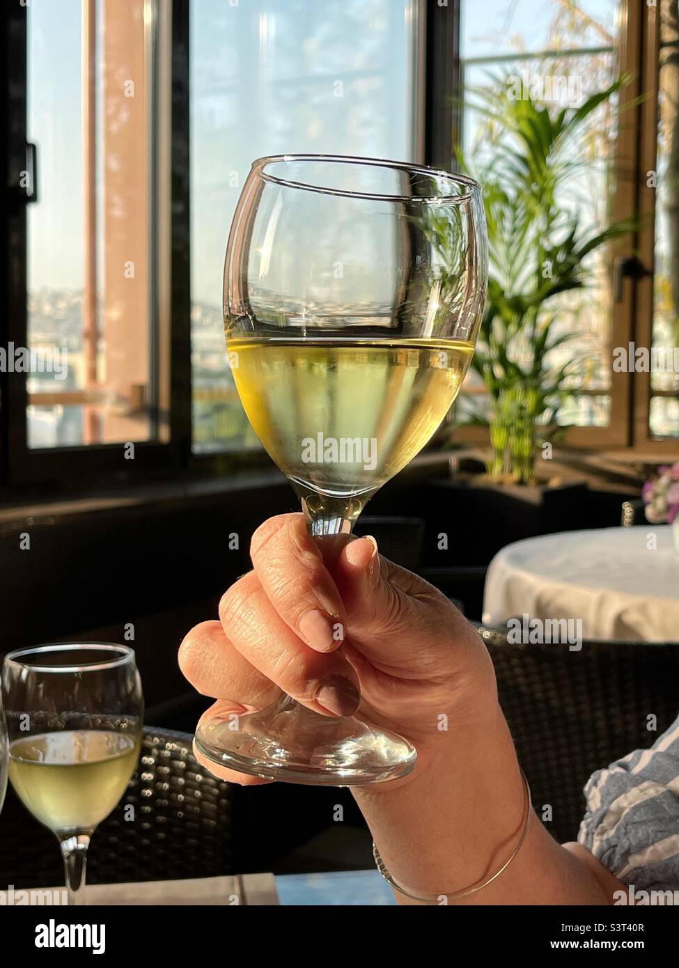 Person holding a glass of chilled white wine in a rooftop bar Stock Photo