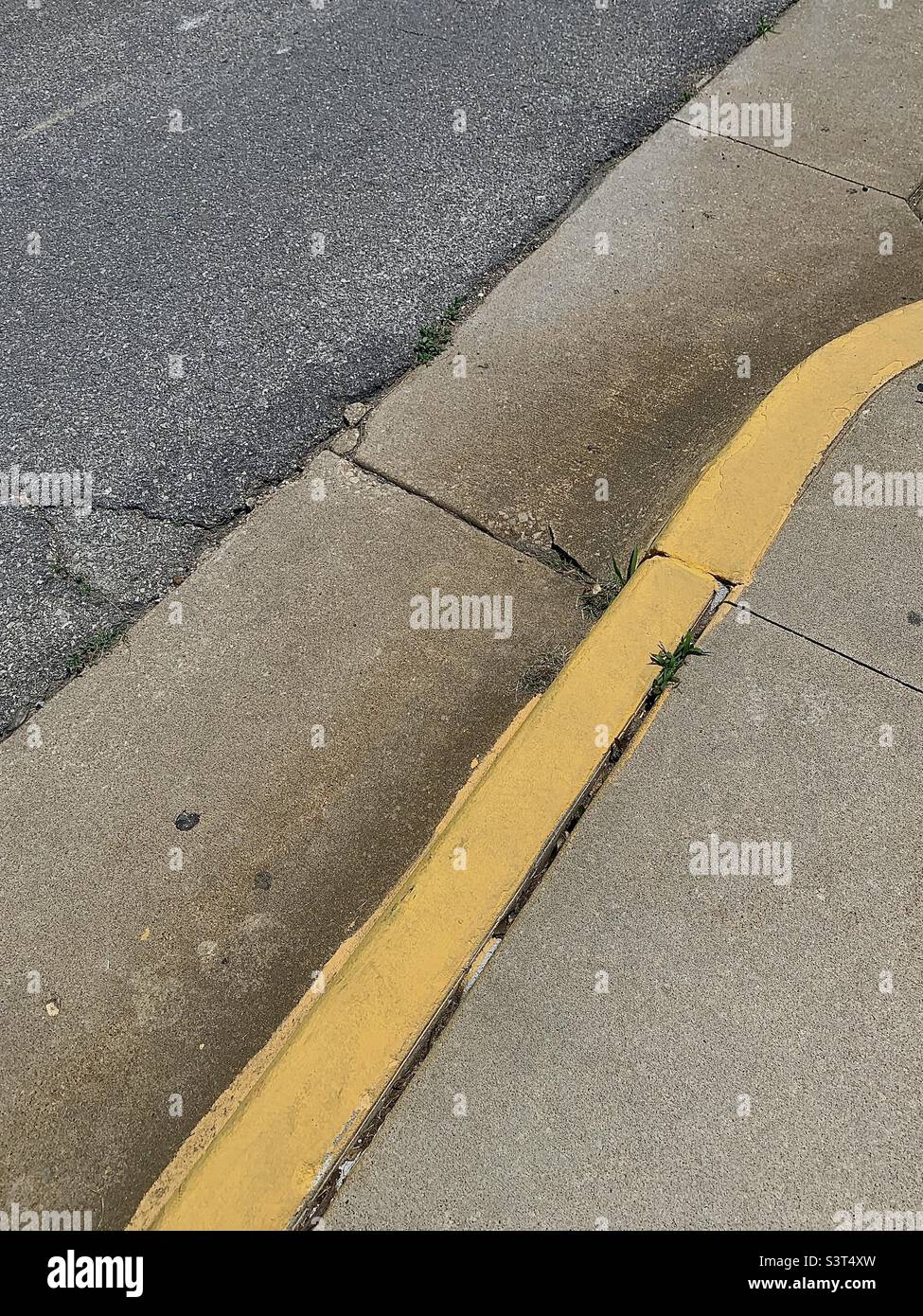 Yellow line on curb next to blacktop road Stock Photo Alamy