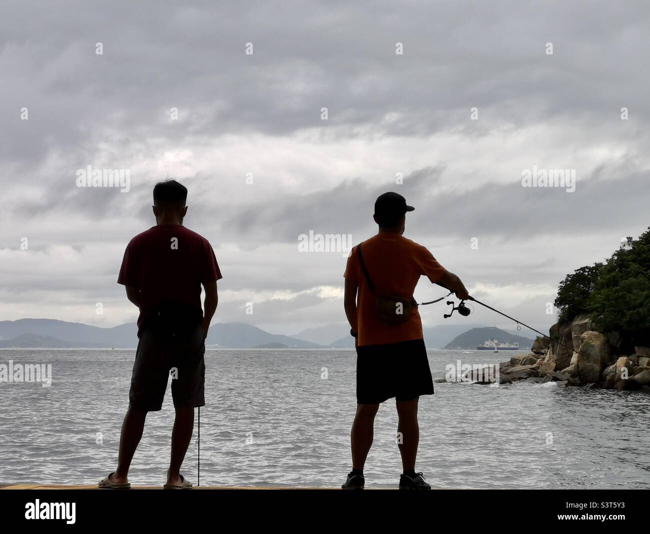 Local men fishing from the Yung Shue Wan pier on Lamma island, Hong Kong. Stock Photo