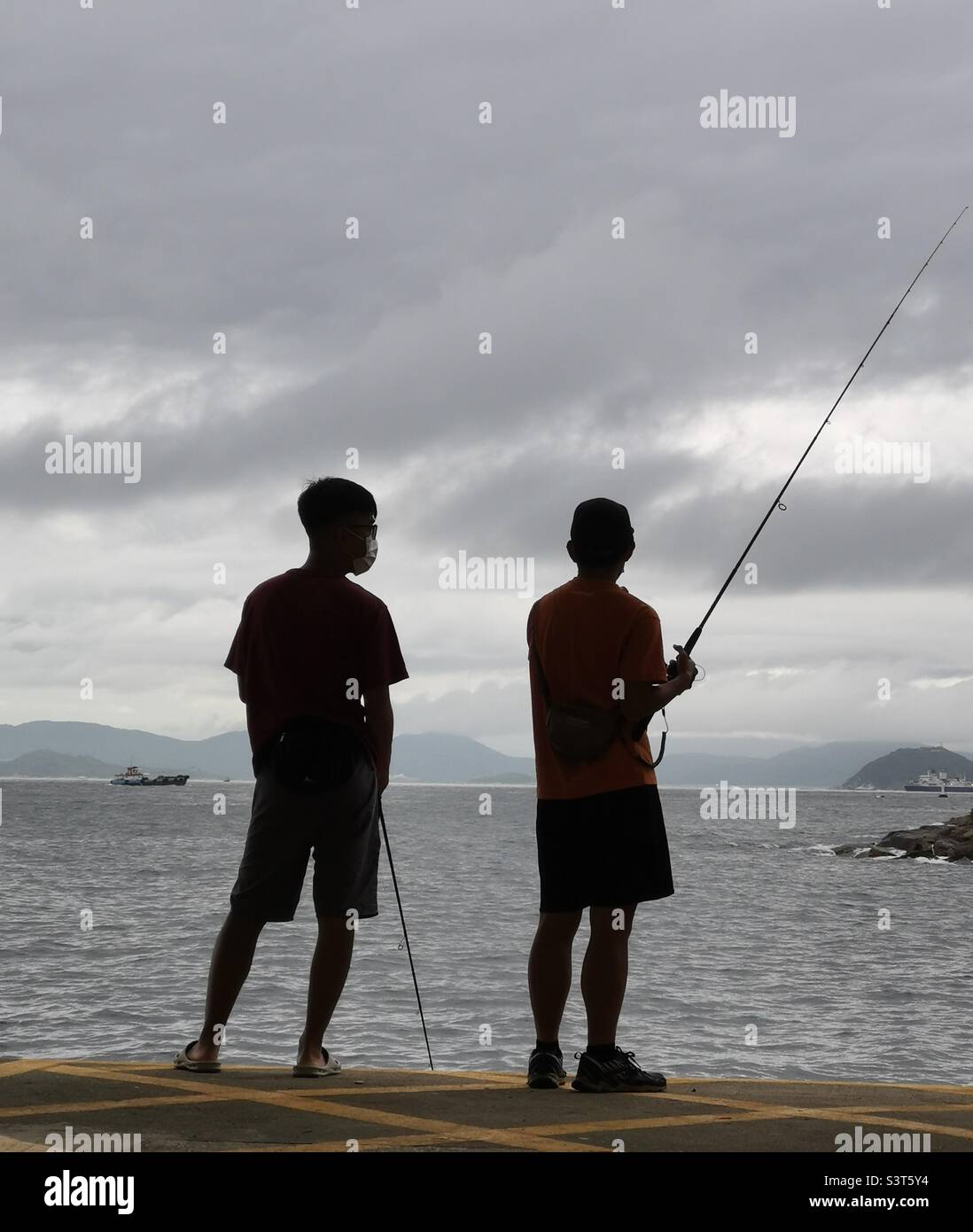 Local men fishing from the Yung Shue Wan pier on Lamma island, Hong Kong. Stock Photo