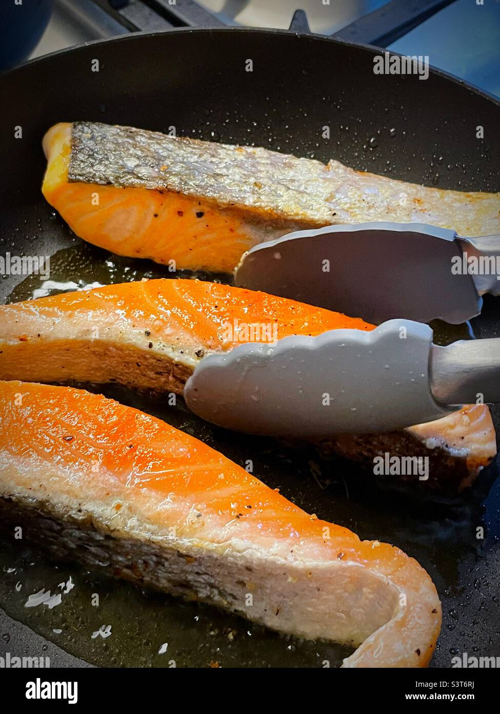 Salmon fillets being seared in a sauce pan, 2022, USA - Smartphone Captured Stock Image