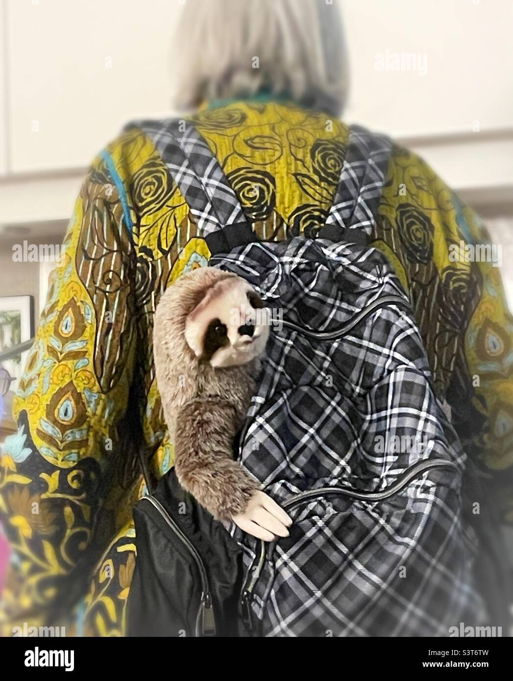 Plushy sloth stuffed animal hanging out of a woman’s backpack, New York City, USA, 2022 - Smartphone Captured Stock Image