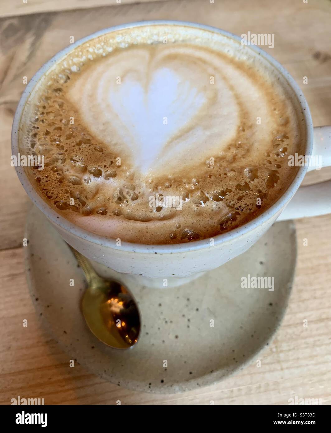 Frothy heart shaped coffee art on cup of coffee Stock Photo