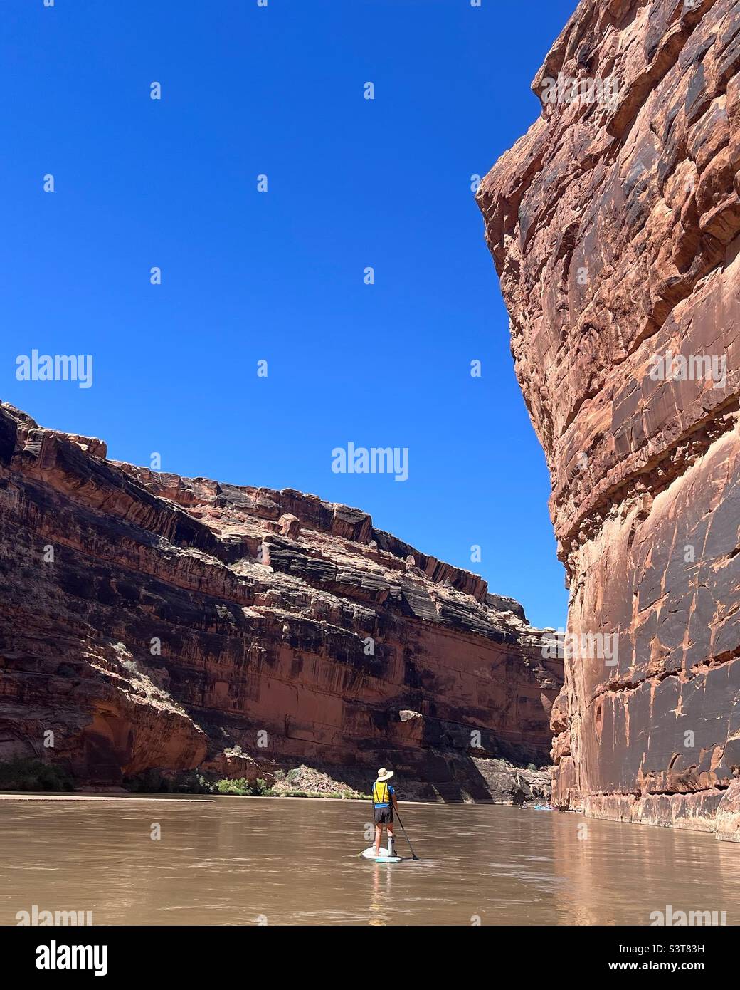 Paddle boarding down the dramatic red rock canyons of the the San Juan River in southern Utah - Smartphone Captured Stock Image