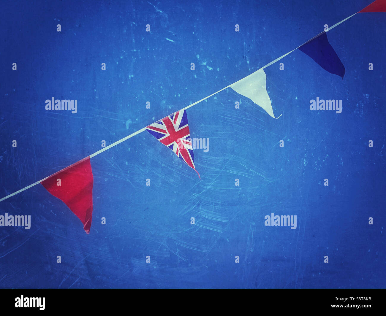A retro effect image of Union Jack bunting, flapping in an English blue sky. This bunting was to celebrate the Queens Platinum Jubilee in June 2022. Photo ©️ COLIN HOSKINS. Stock Photo