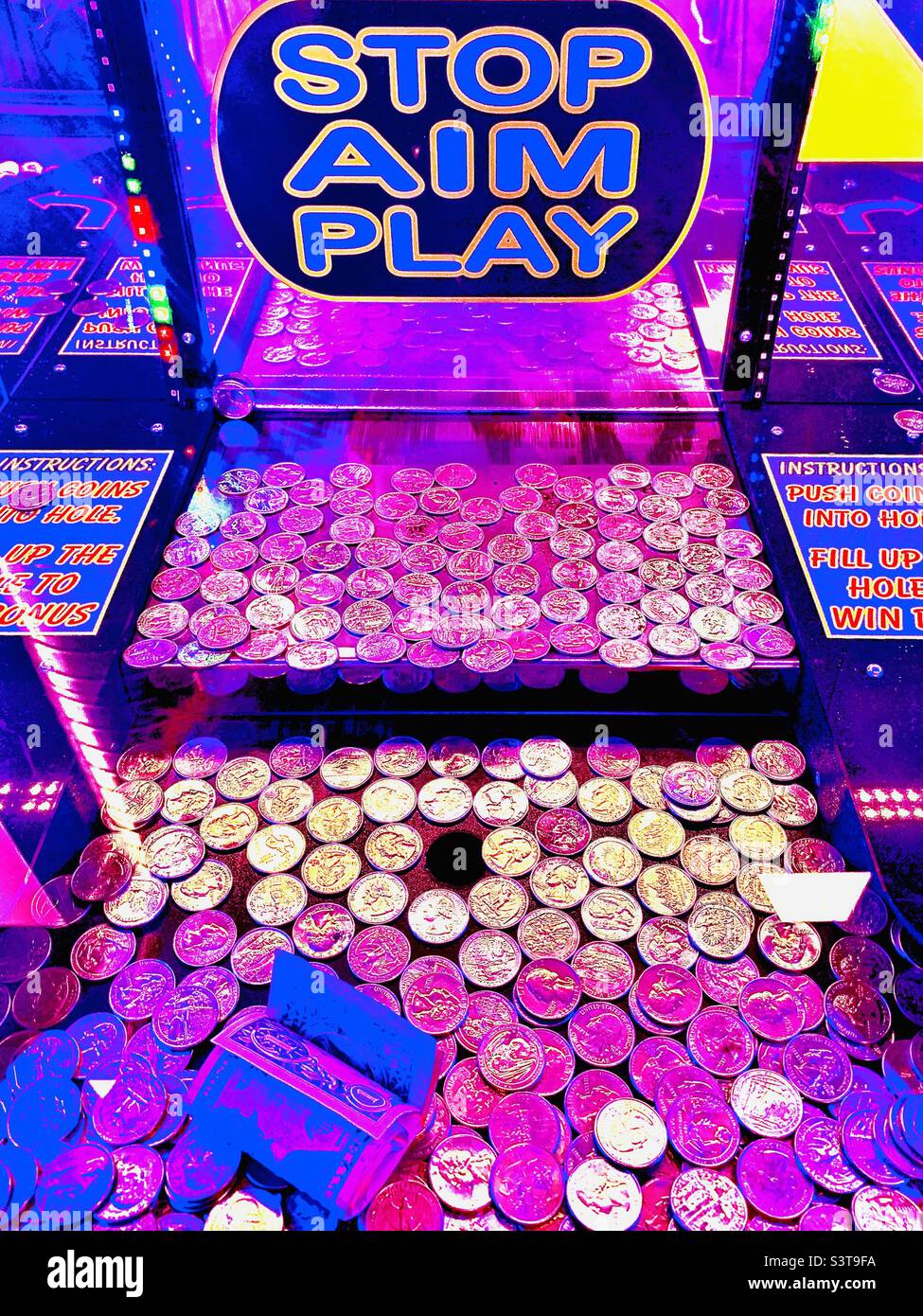 Slot machine game with purple tint, full of quarters Stock Photo